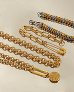 Varias pulseras de cadenas doradas y bicolores sobre fondo claro, una con medallón redondo colgante.