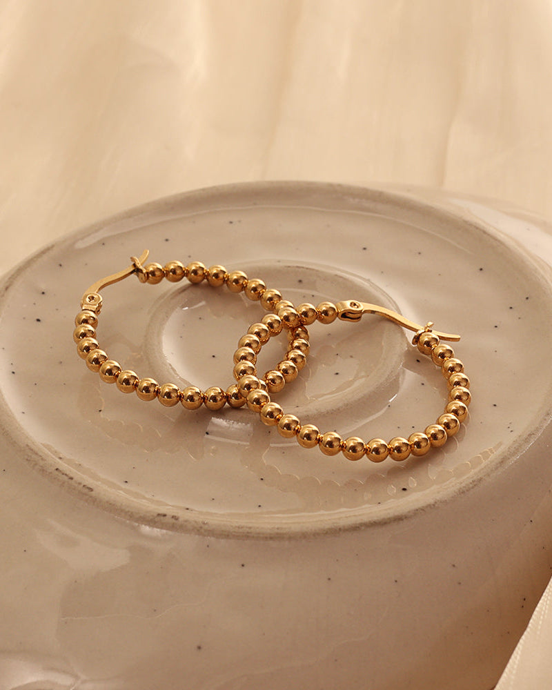 Detalle de aretes Arco con acabado dorado