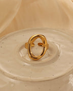Anillo dorado de gran óvalo abierto y bordes redondeados, sobre un plato de cerámica claro.