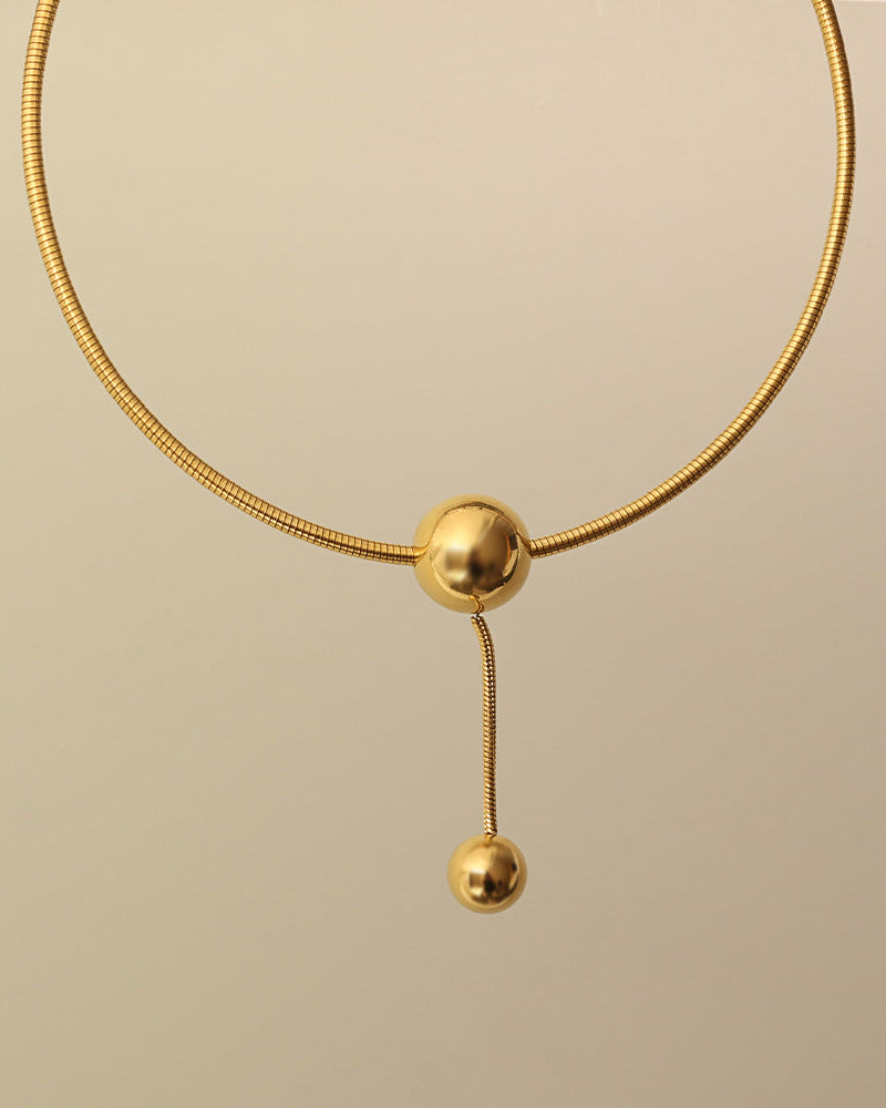 Detalle de collar Órbita Lariat con acabado dorado