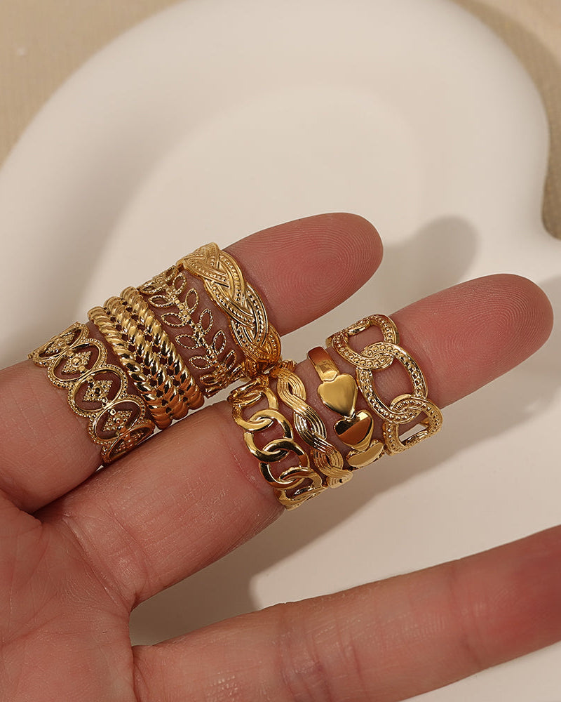 Varios anillos dorados de eslabones y bandas decoradas, sostenidos sobre los dedos de una mano.