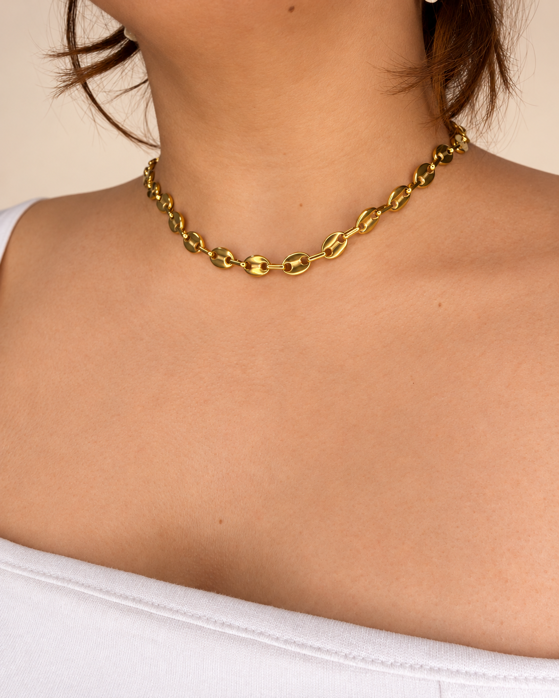 Collar corto dorado de Xihe By Dm con eslabones ovalados pulidos y conectores alargados, lucido por una modelo con blusa blanca.