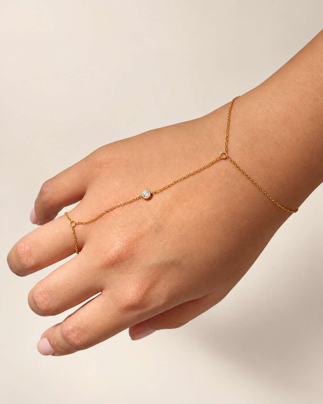 Pulsera anillo de Xihe By Dm con cadena fina dorada y una piedra redonda brillante sobre el dorso de la mano.